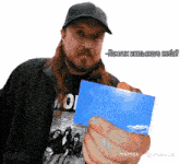 a man with long hair and a beard is holding a piece of paper with a picture of a band on it