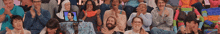 a large group of people are sitting in a row with their hands in their faces