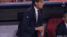 a man in a suit is sitting in a stadium holding a bottle