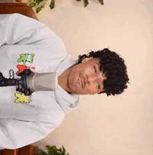 a person with curly hair wearing a hoodie that says gnx on it is singing into a microphone