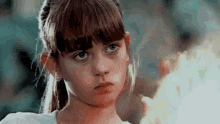 a close up of a girl 's face with a fire in her hand