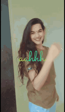 a girl with long hair is smiling and dancing with the word ahhhh written on the wall behind her