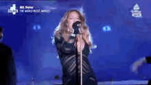 a woman is singing into a microphone on stage .