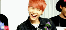 a young man with red hair is laughing while holding flowers in his hand .