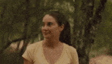a woman in a yellow shirt is standing in the woods and says what ?