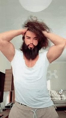 a man with a beard and long hair is holding his hair .