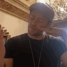 a man wearing a hat and a necklace is making a gesture
