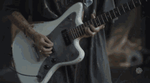 a person is playing a white guitar with a sticker on the bottom that says ' let 's talk rock '