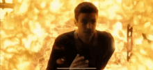 a man is standing in front of a fire .
