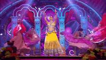 a woman in a yellow dress is dancing on a stage with other people .