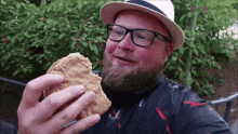 a man with a beard and glasses is eating a chicken sandwich