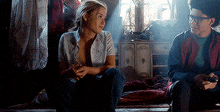 a man and a woman are sitting on the floor in a dark room talking to each other .