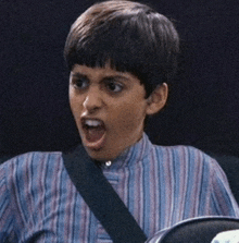 a young boy wearing a striped shirt with a black strap around his neck