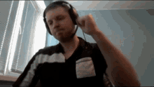 a man wearing headphones is sitting in front of a window with blinds