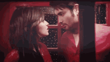 a man and woman are kissing in a red room