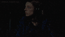 a woman wearing headphones and a blue jacket looks down