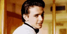 a young man in a tuxedo and bow tie is standing in a room .