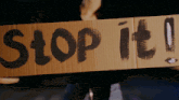 a person holding a cardboard sign that says " stop it "