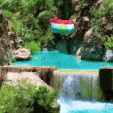 a flag is hanging over a waterfall in a canyon