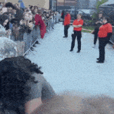 a woman in a red shirt stands in a crowd of people