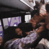 a woman in a purple shirt is fighting another woman in a bus