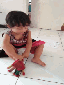 a little girl is playing with a red glove