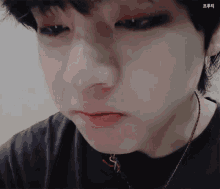 a close up of a young man 's face with a necklace around his neck .