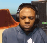 a man wearing headphones and a blue hoodie is looking down .