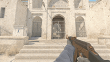 a person holding a gun in front of a building with a cage in the background