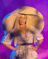 a woman wearing a very large hat and a white dress with her hands on her hips