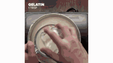 a person is pouring gelatin into a glass bowl on top of a pot .