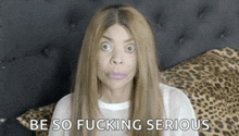 a woman is sitting on a bed with a leopard print pillow and says be so fucking serious