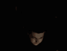 a close up of a person 's face in the dark with a light shining on it .