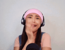a woman wearing headphones and a pink hat is making a face