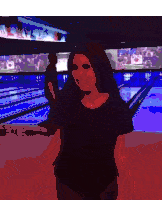 a woman is standing in a bowling alley and smiling
