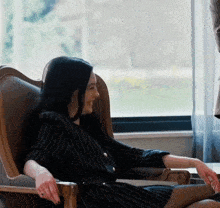 a woman sits in a chair with her legs crossed