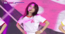 a woman in a white t-shirt is dancing on a stage with her hands on her hips .