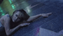 a woman is laying on the floor with her arms outstretched and a tattoo on her arm .