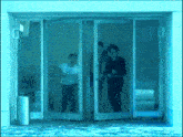 three people are walking through a glass door