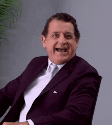 a man in a suit and tie is sitting in a chair with his mouth open
