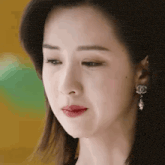 a close up of a woman 's face wearing earrings and looking at the camera .