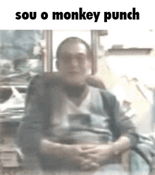 a blurry picture of a man sitting in a chair with the words `` sou o monkey punch '' on the bottom .