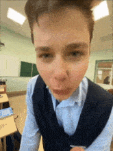 a young man making a face in a classroom with a green board in the background