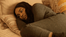 a woman is laying on a bed with her head on a pillow and looking at the camera .