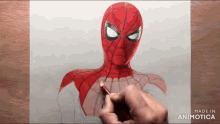 a person is drawing a spiderman with a pencil on a piece of paper