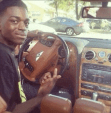a man sitting in a bentley car giving a thumbs up