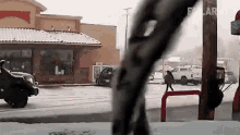 a truck is driving down a snow covered street in front of a restaurant .