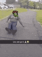 a man is riding a skateboard down a road with a picture of a monster on his shirt .