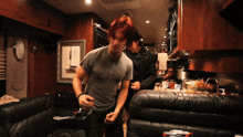 a man in a gray shirt is dancing in a room