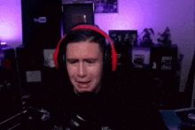 a man wearing headphones is crying in front of a microphone in a room .